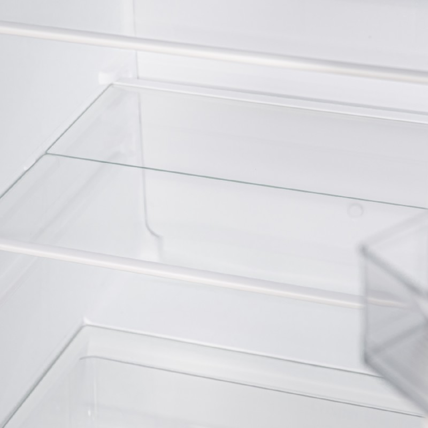 Puste wnętrze lodówki ze szklanymi półkami i przezroczystą szufladą.