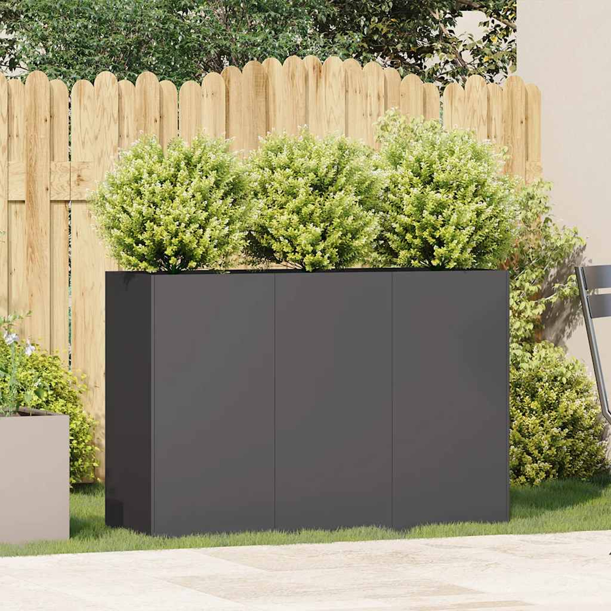 Dunkelgrauer Schrank mit drei Türen, mit grünen Büschen oben, in einer Gartenszene.