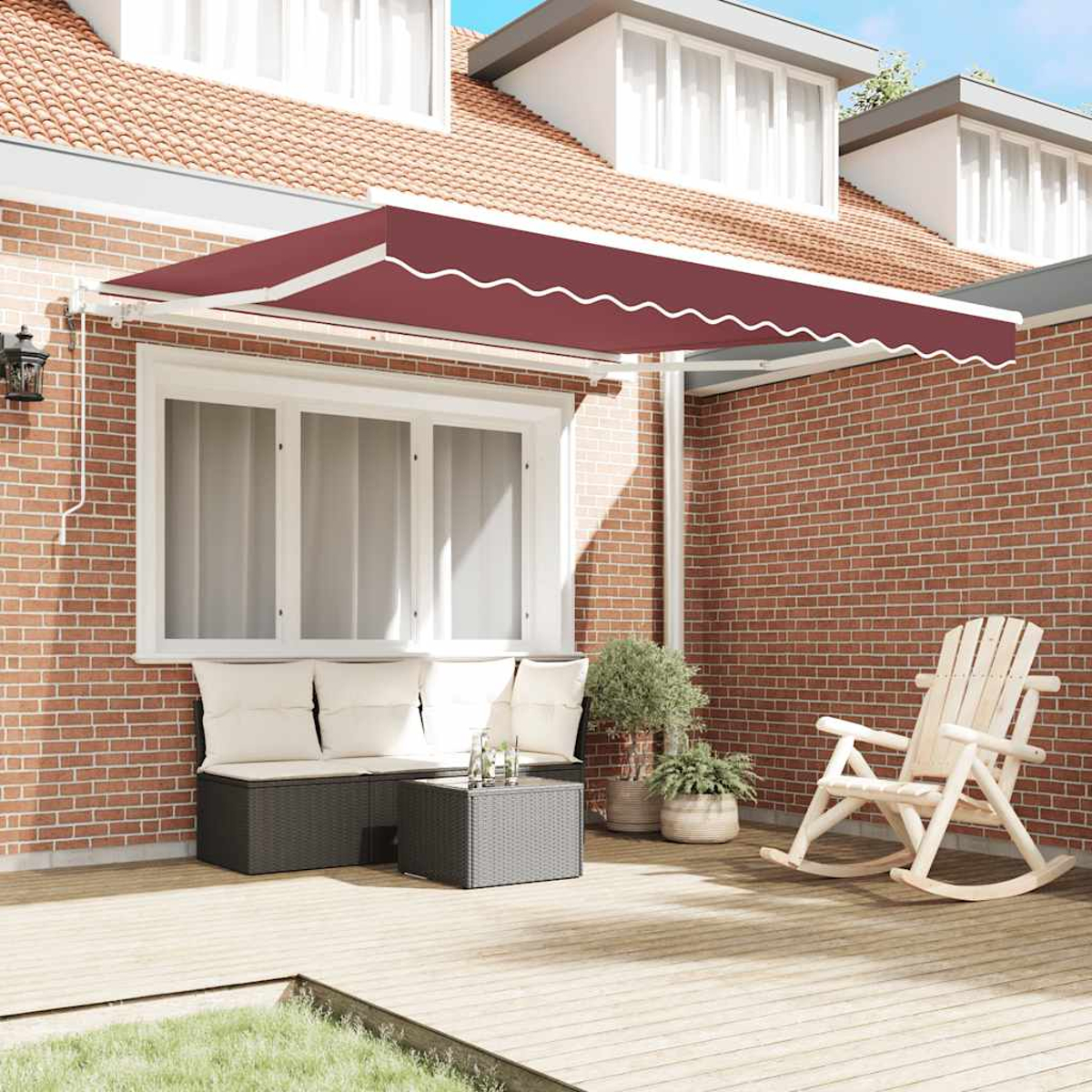 Eine rote Markise über einer Terrasse, mit Gartenmöbeln.