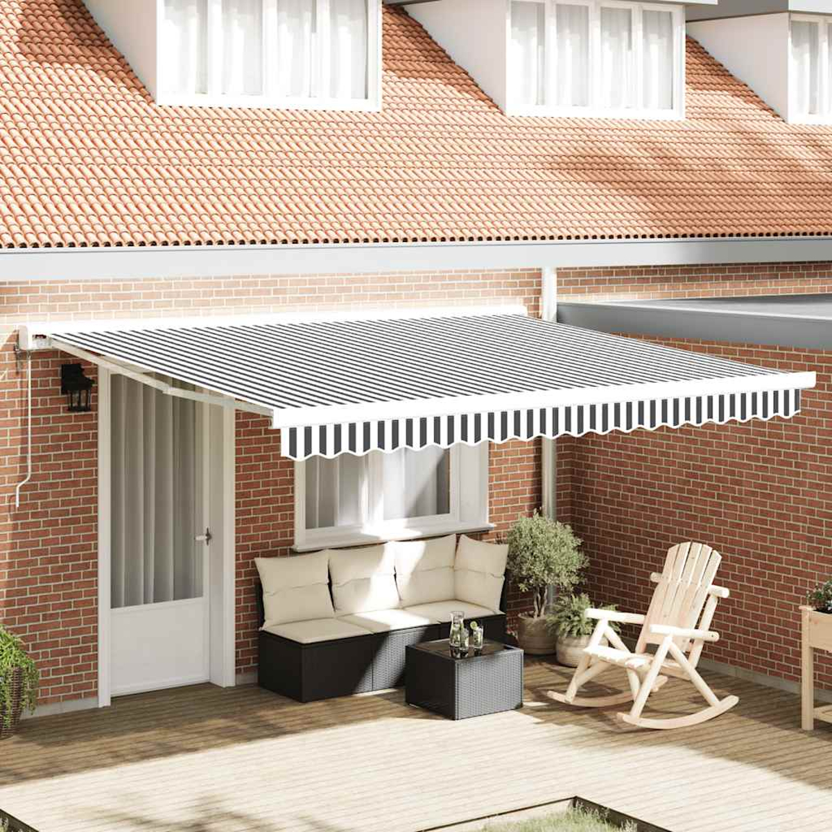 Ein Haus mit gestreifter Markise und Gartenmöbeln auf einer Terrasse.