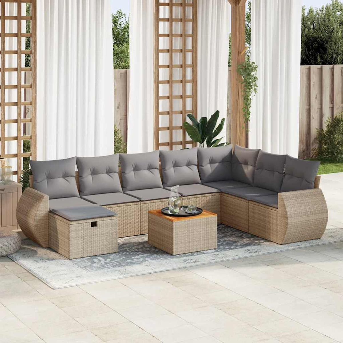 Zona salotto all'aperto con mobili in vimini beige, cuscini grigi e tende.