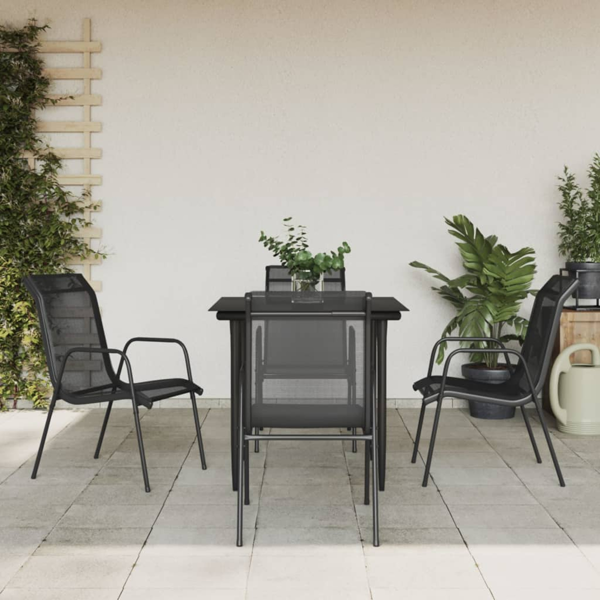 Outdoor-Setting. Schwarzer Tisch mit vier schwarzen Netzstühlen. Pflanzen im Hintergrund.