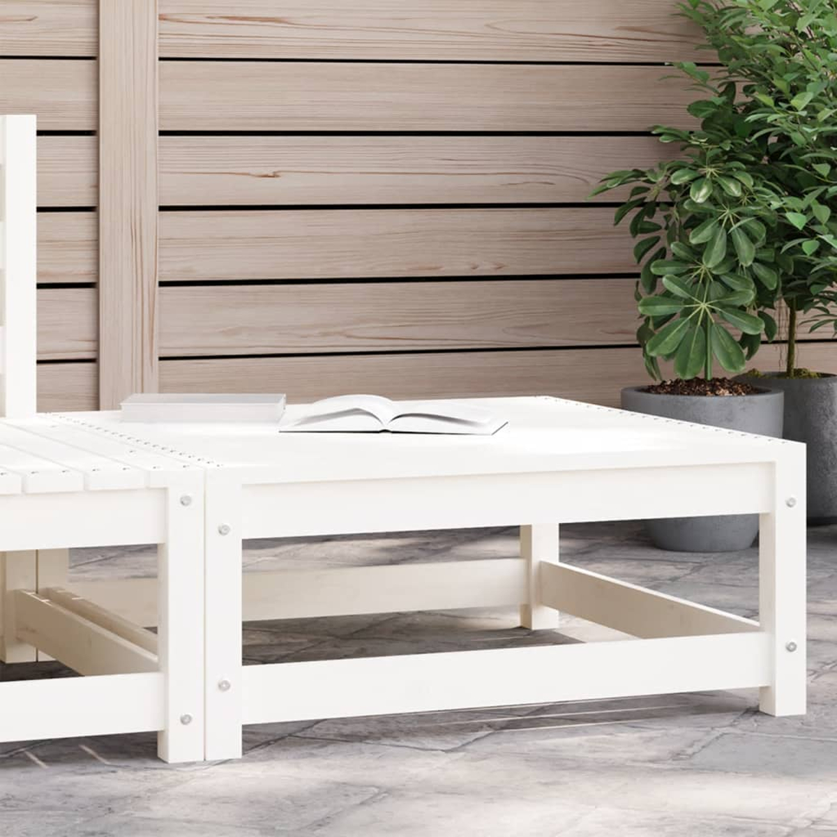 Weißer quadratischer Couchtisch aus Holz im Freien. Offenes Buch oben drauf. Natürlicher Hintergrund.