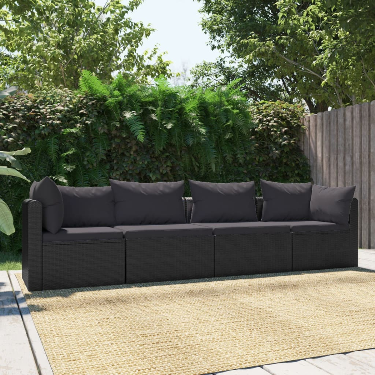 Schwarzes gewebtes Outdoor-Sofa mit Kissen. Das Sofa steht auf einem beigefarbenen Teppich, Bäume im Hintergrund.