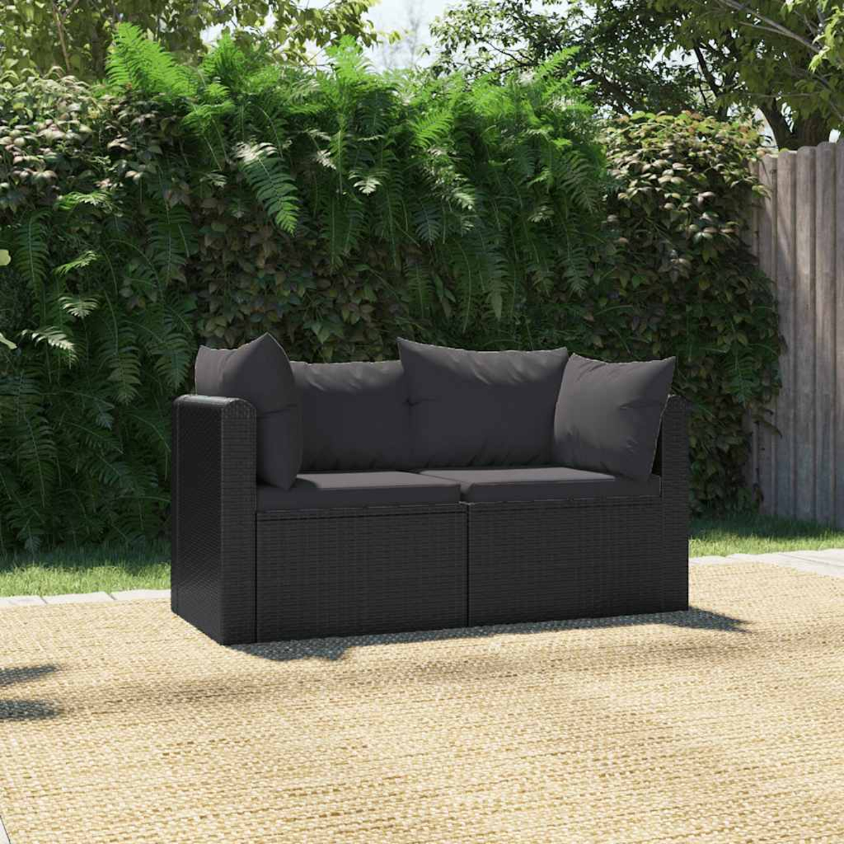 Gartenset: dunkelgraues Sofa auf einem Teppich, grüner Hintergrund, Farne und Zaun.