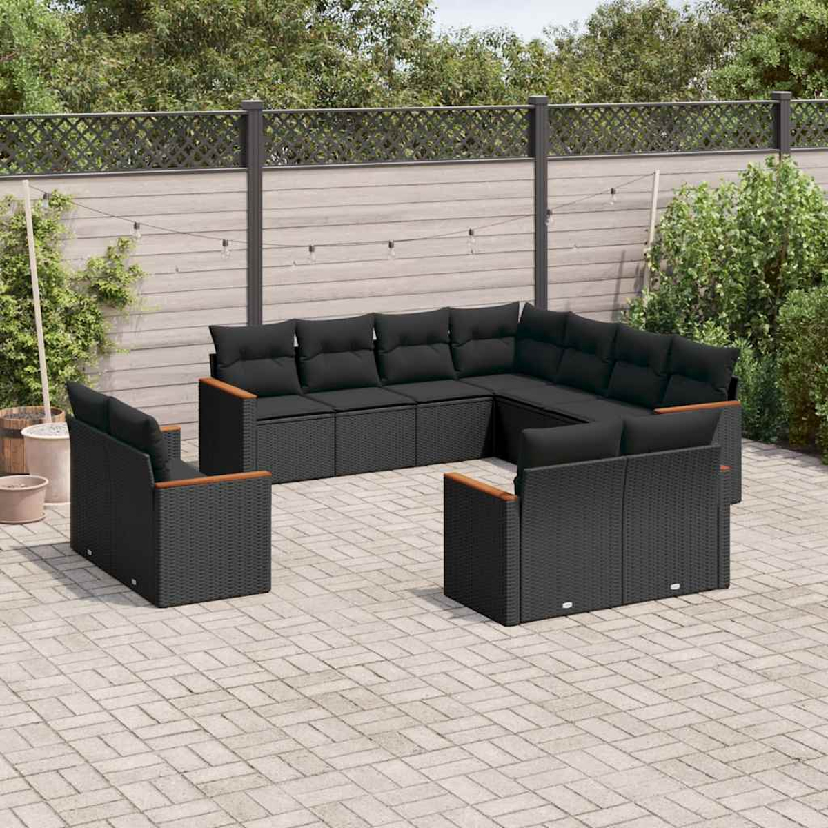 Outdoor-Ecksofa-Set aus schwarzem Korbgeflecht mit Kissen, in einem Garten.