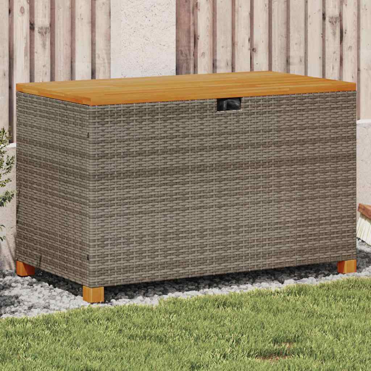 Eine Aufbewahrungsbox aus Korbgeflecht mit Holzdeckel, platziert in einem Garten. Im Hintergrund sind ein Zaun und Gras zu sehen.
