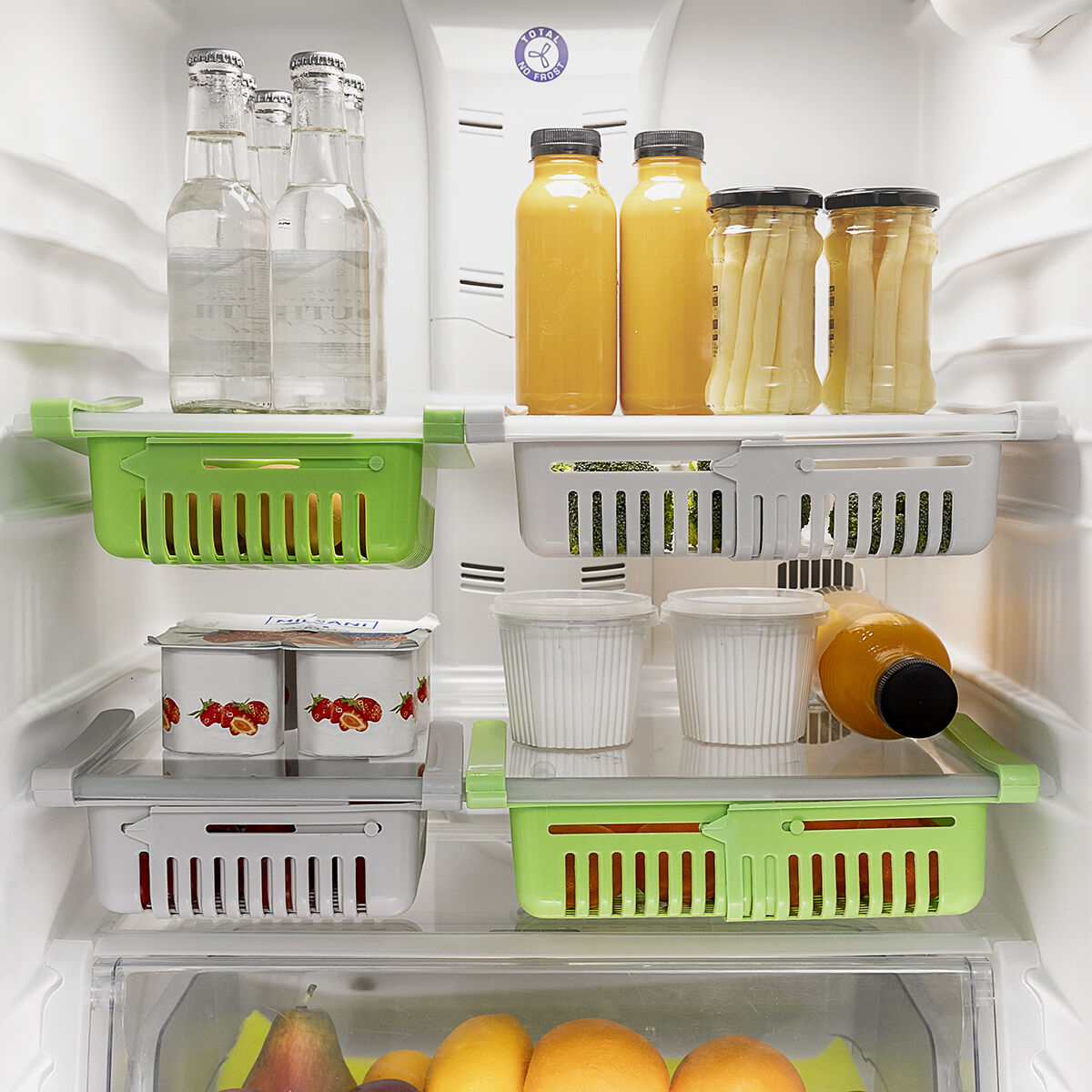 Kühlschrank voller Lebensmittel: Getränke, Saft, Gurken und Behälter auf Regalen. Grüne und weiße Organizer.