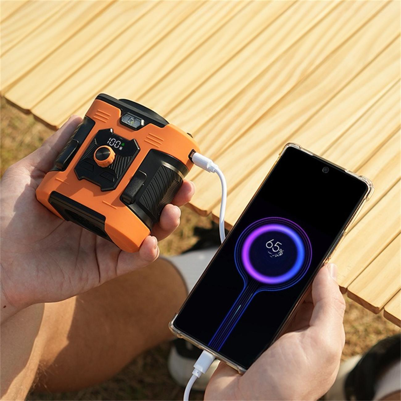 Eine Person hält eine orangefarbene Powerbank, die ein Telefon auflädt. Das Telefon zeigt ein Ladesymbol.