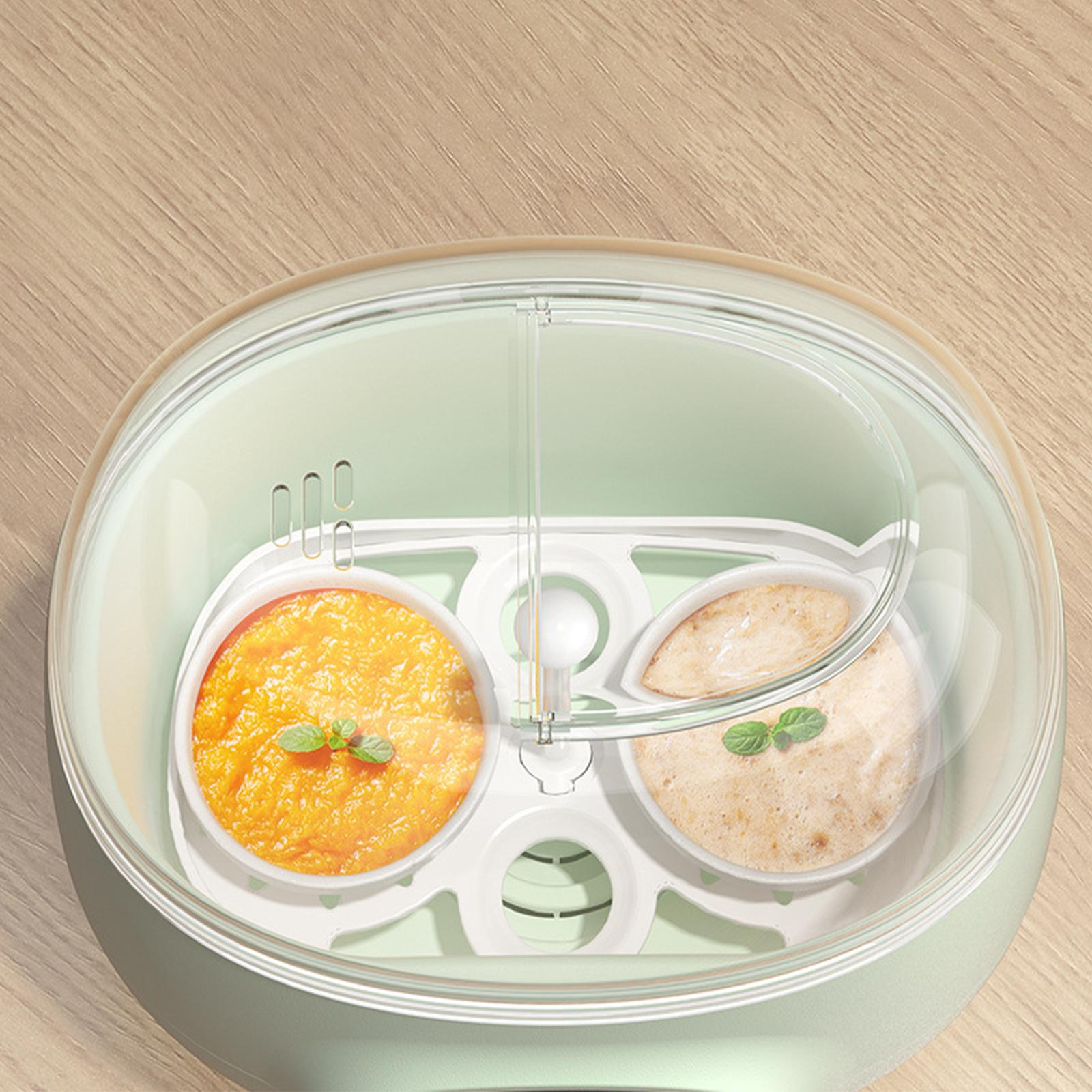Babykostwärmer mit zwei Schalen, eine orange, eine beige. Klarsichtdeckel. Der Hintergrund ist eine Holzoberfläche.