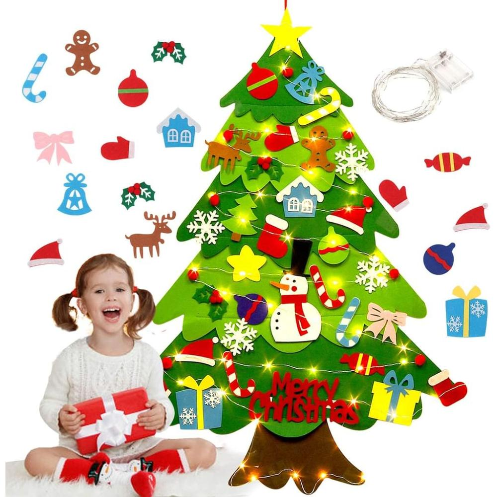 Ein Mädchen mit Geschenk lächelt. Ein Weihnachtsbaum aus Filz hat Dekorationen. Dekorationen umfassen einen Schneemann, Geschenke und Zuckerstangen.
