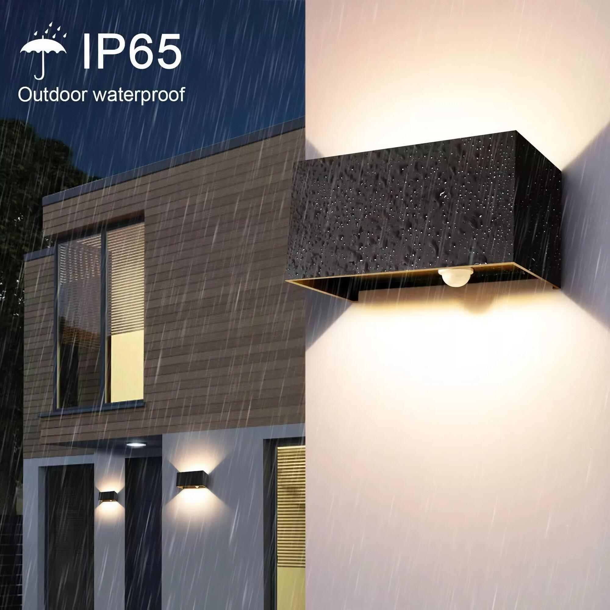 Schwarze Außenleuchte an einer weißen Wand, mit Regen und einem IP65 wasserdicht-Label.