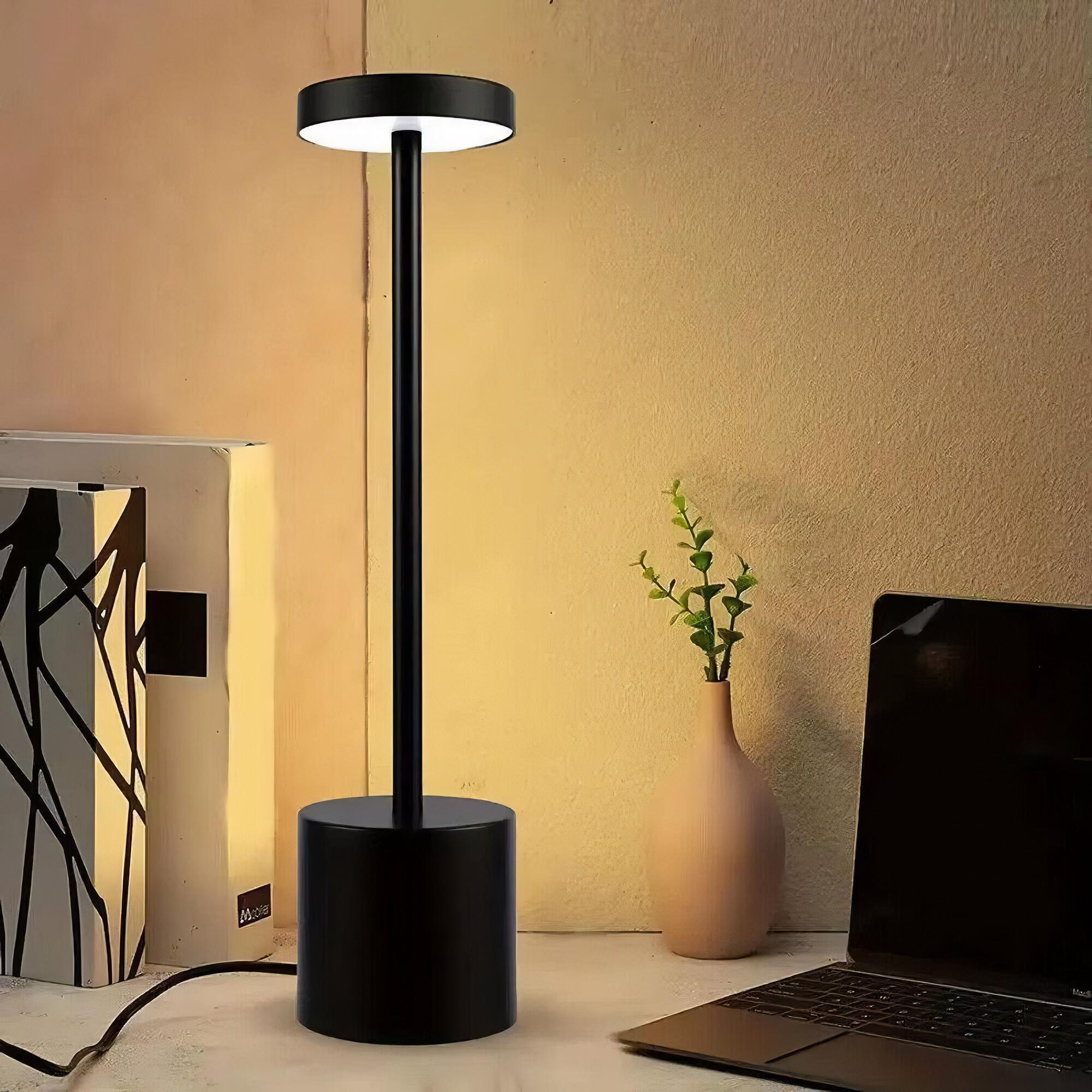 Schwarze Schreibtischlampe mit zylindrischem Fuß und langem vertikalen Ständer, auf einem Schreibtisch.
