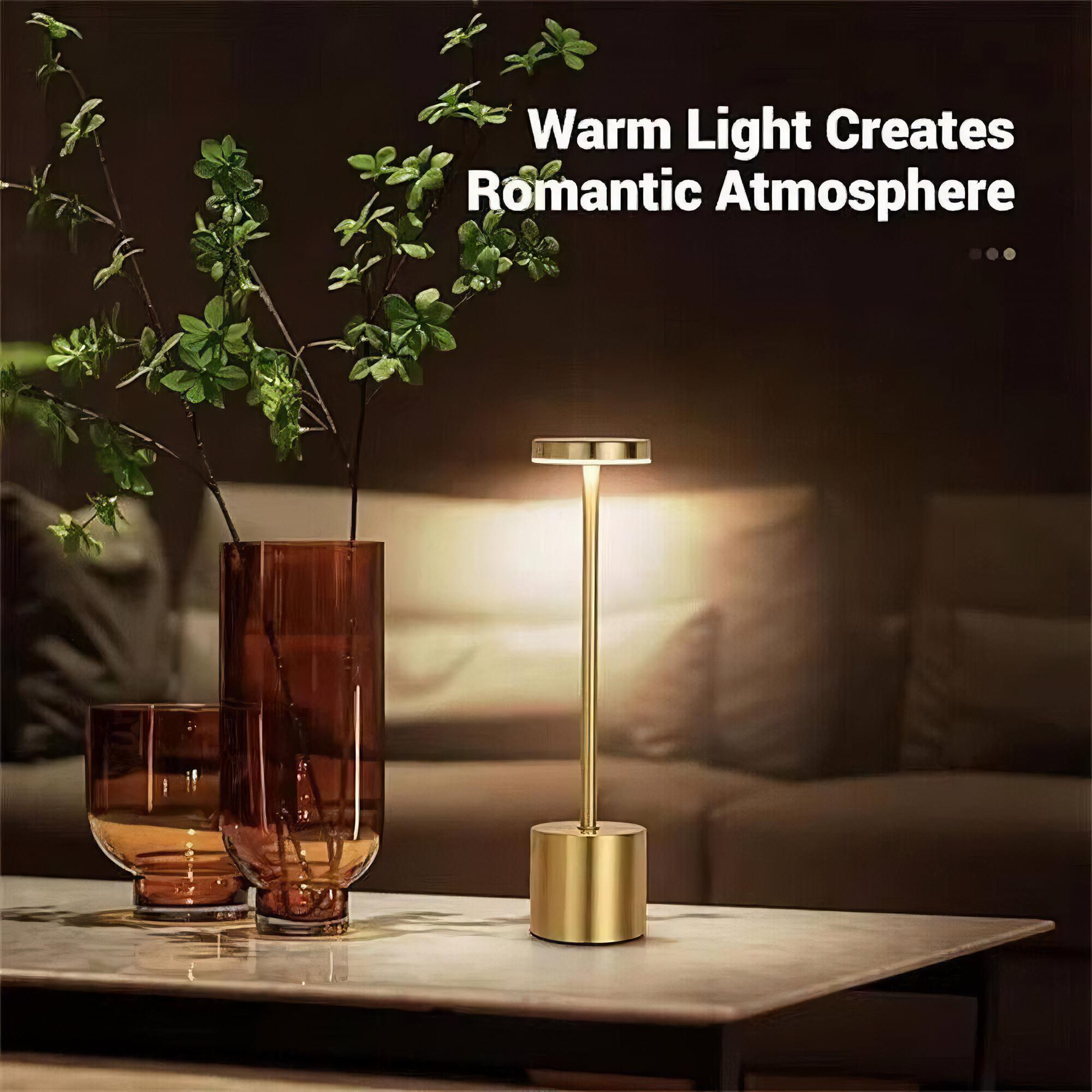 Goldene Tischlampe auf einem Tisch mit einer Vase, zwei Gläsern und einem Sofa im Hintergrund. Text: Romantische Atmosphäre.