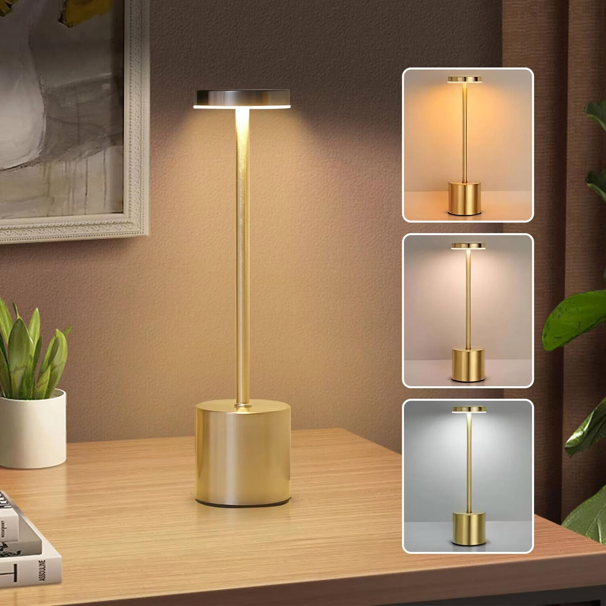 Goldene Schreibtischlampe mit drei Lichteinstellungen. Die Lampe steht auf einem Holztisch.