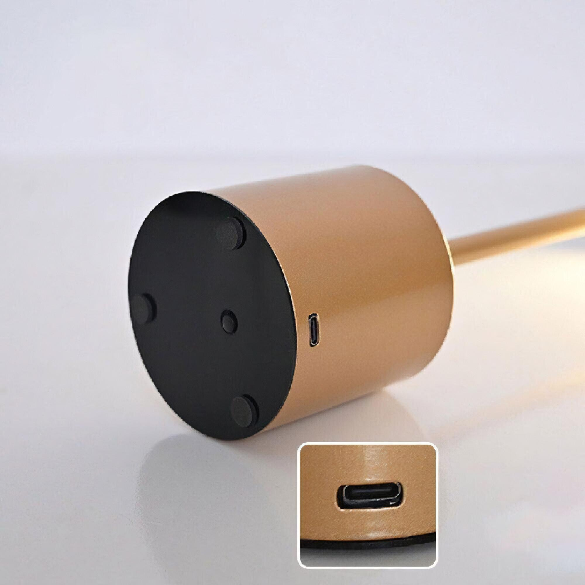 Der Fuß einer goldenen Schreibtischlampe mit USB-Anschluss, Nahaufnahme. Schwarzer Sockel.