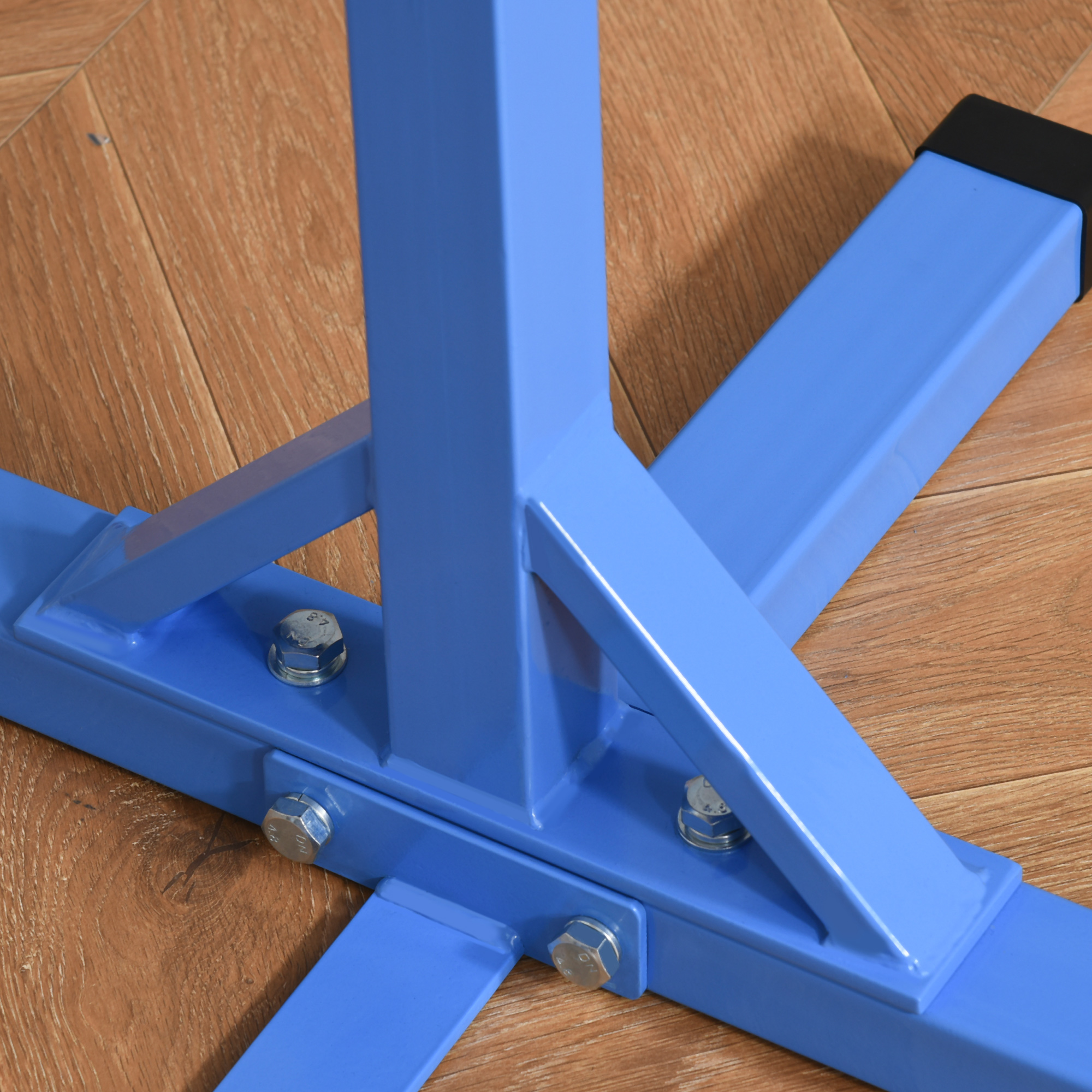 Primer plano de un marco de metal azul con pernos sobre un piso de madera. El marco es parte de una estructura de gimnasia.