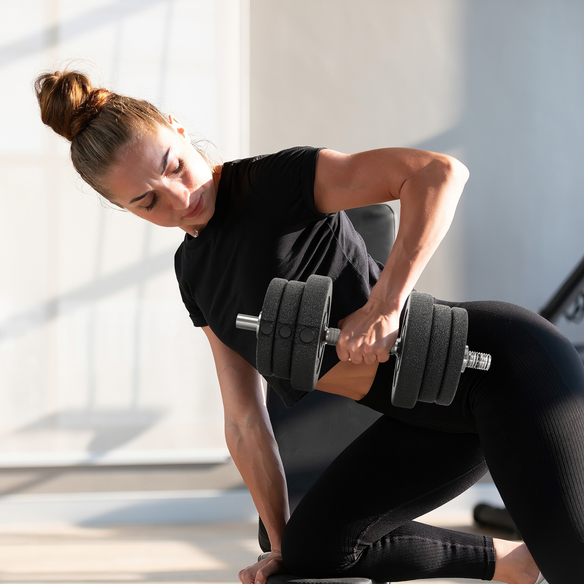 Donna in nero che si esercita con un manubrio in palestra.