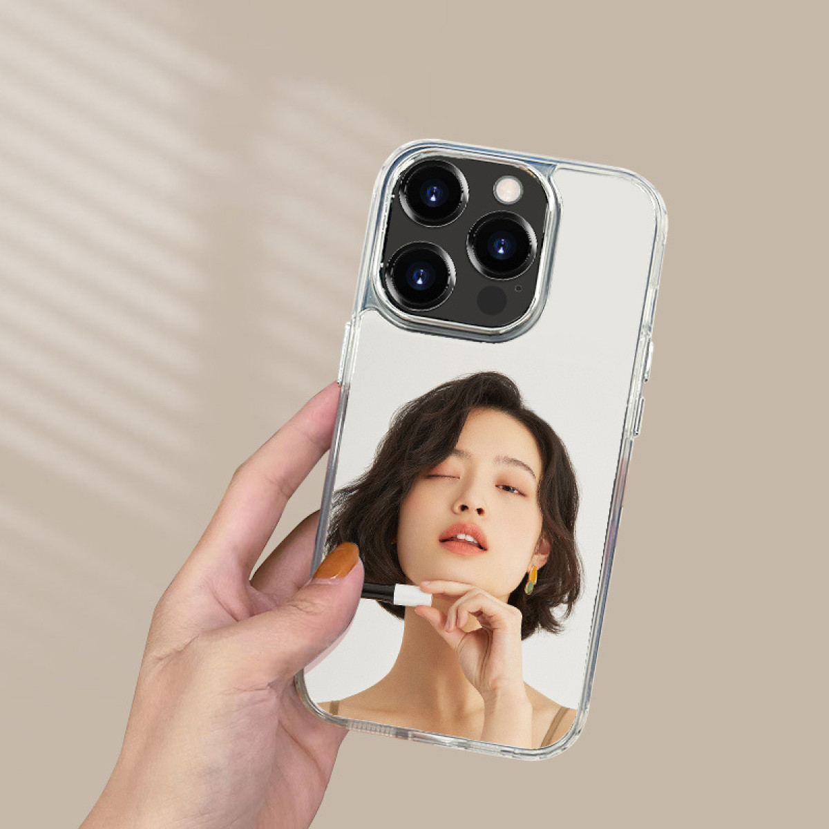 Eine Person, die ein Telefon mit einer transparenten Hülle hält und ein Bild einer Frau darin.