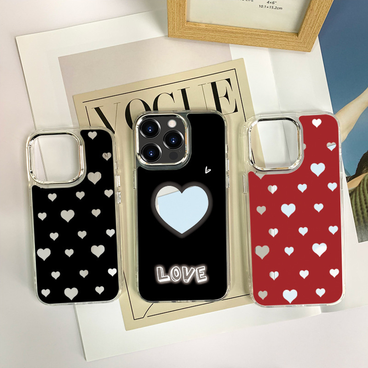 Tre custodie per telefono con diversi design a cuore: nero con cuori bianchi, nero con un cuore e rosso con cuori.