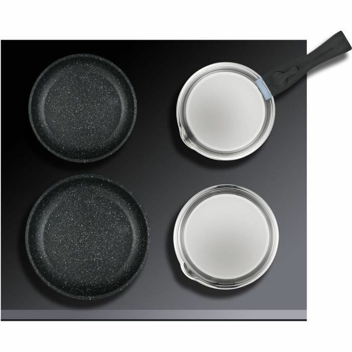 Vier Pfannen auf einer schwarzen Oberfläche. Zwei sind schwarz und strukturiert; zwei sind weiß mit Deckel.