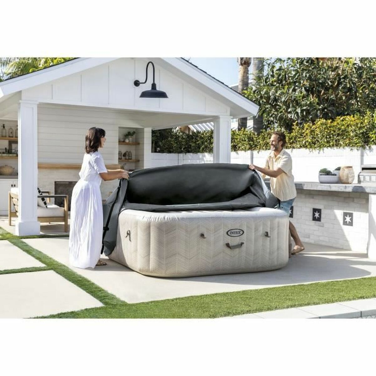 Zwei Personen decken einen Whirlpool ab. Weißes Gebäude im Hintergrund.