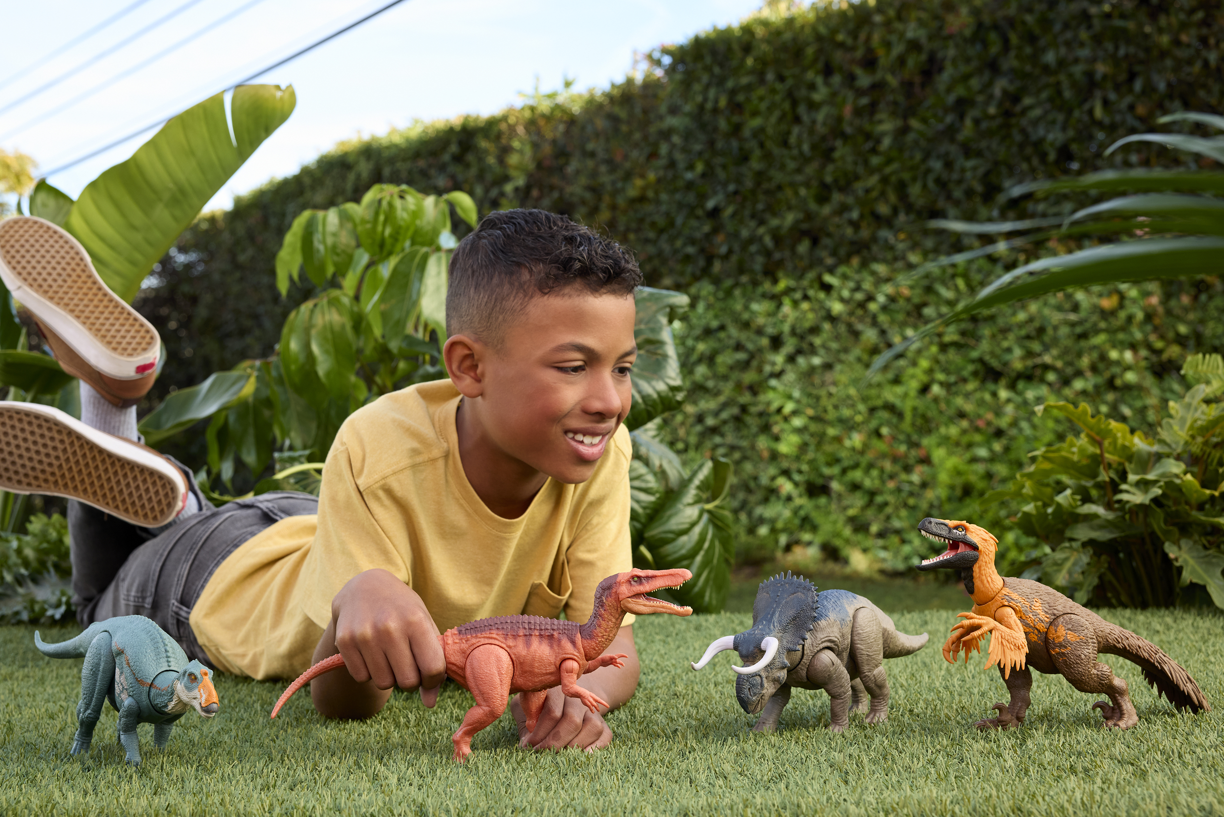 Ragazzo sull'erba con dinosauri, sfondo verde, giornata di sole.