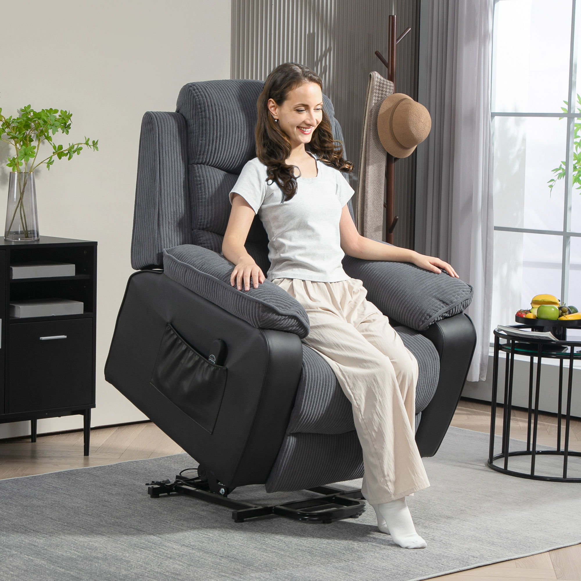 Mujer con camisa blanca y pantalón beige sentada en sillón reclinable gris en sala de estar.