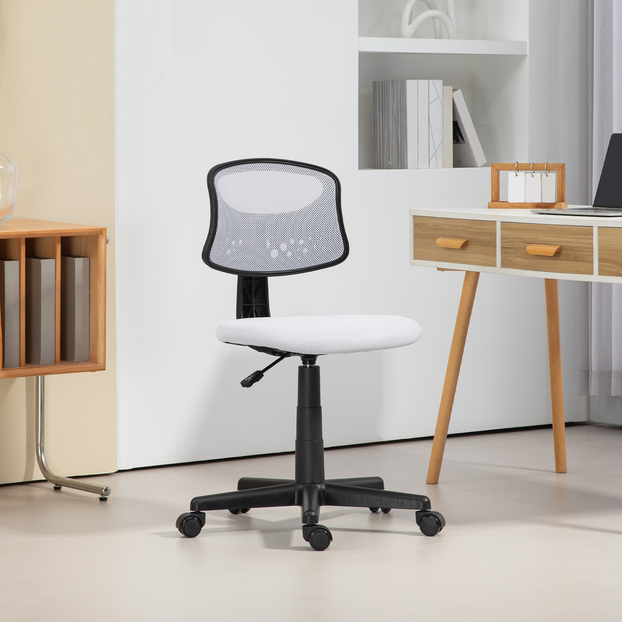 Silla de oficina blanca con respaldo de malla negra y base negra. Frente a un escritorio blanco.