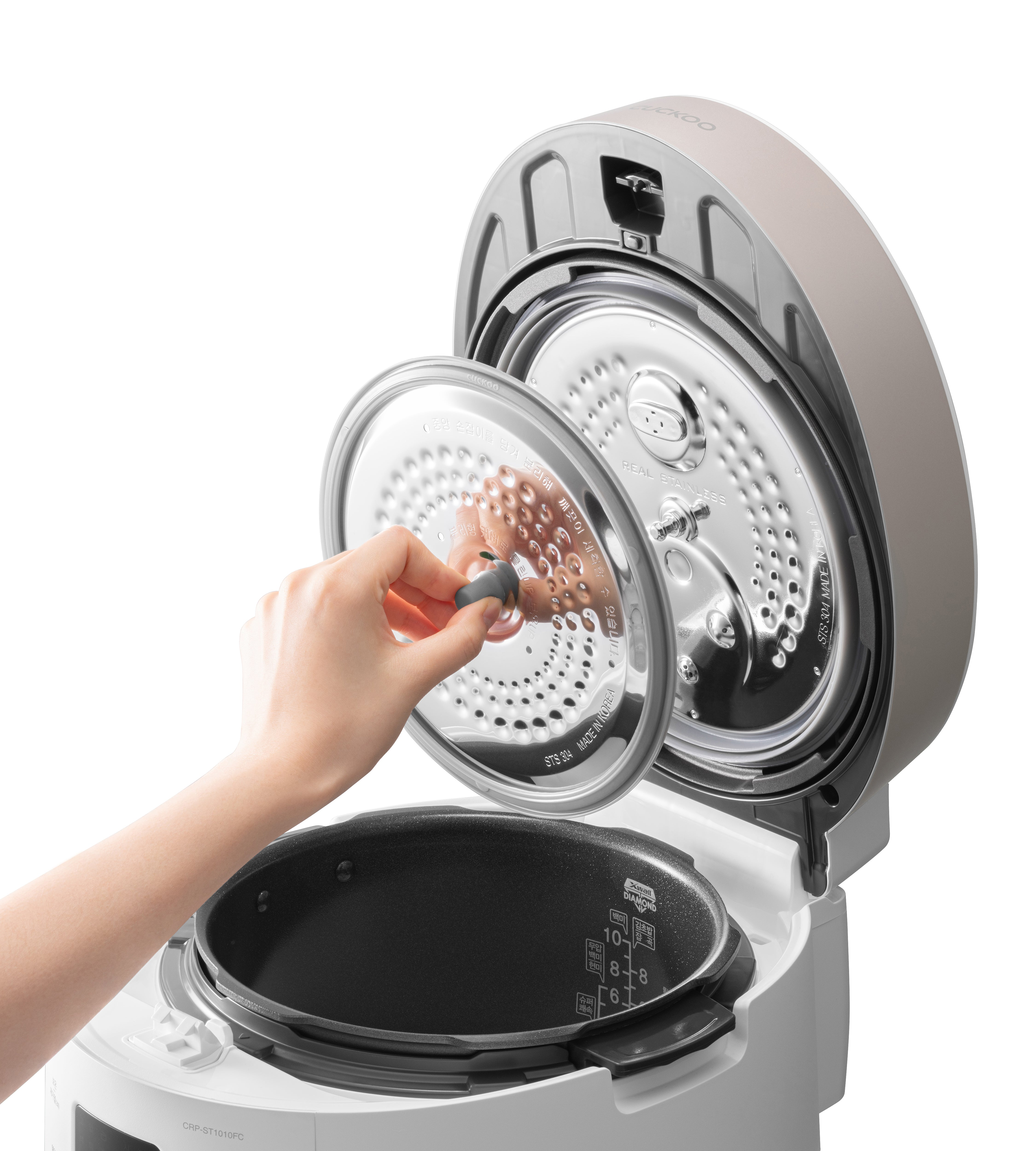 Dłoń trzymająca pokrywę garnka do ryżu, z widocznym wewnętrznym garnkiem.