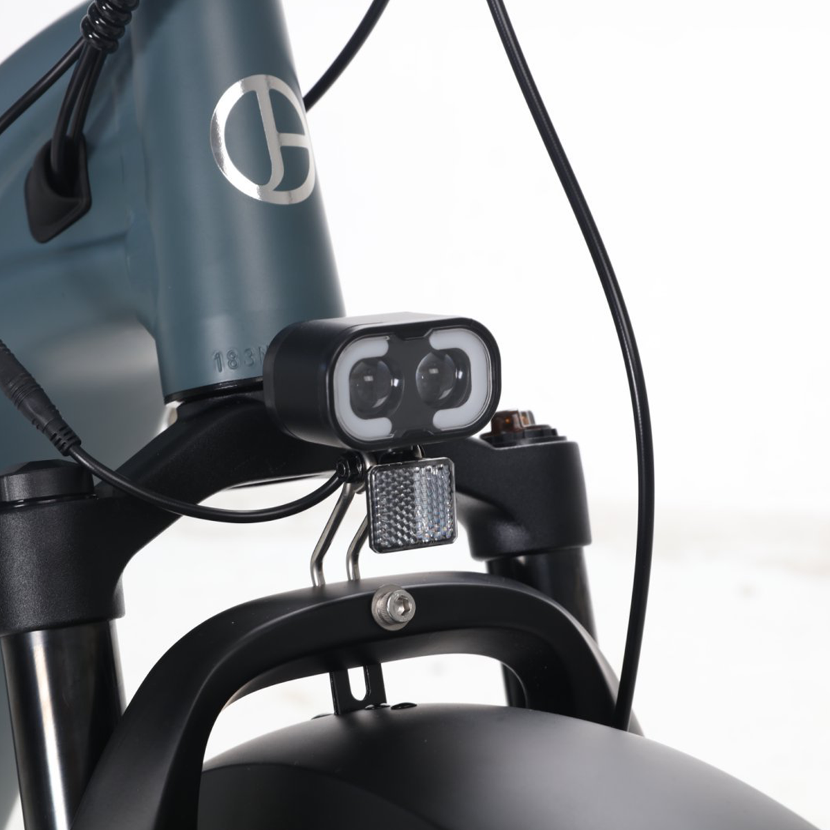 Zbliżenie przodu czarno-szarego roweru z reflektorem i odblaskiem.