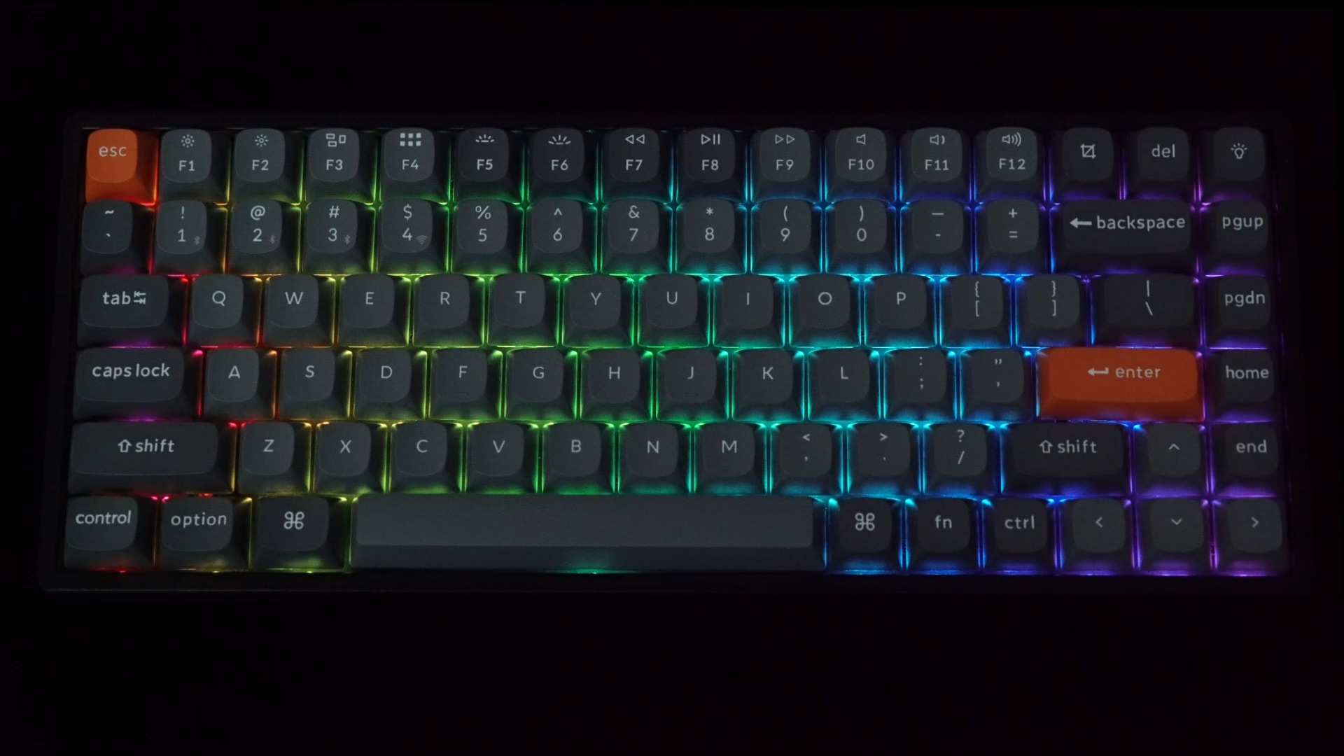 Klawiatura mechaniczna z podświetlonymi klawiszami w tęczowych kolorach na czarnym tle.