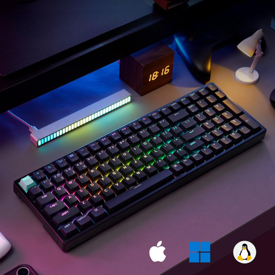 Czarna klawiatura z tęczowymi klawiszami, biurko z lampą, zegarem i motywem gamingowym.