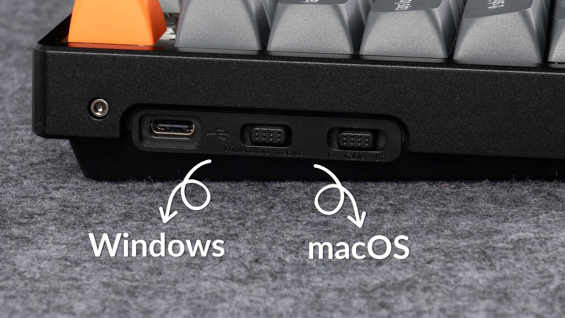 Klawiatura z portami i przełącznikami dla systemów Windows i macOS. Klawiatura ma szarą powierzchnię z tekstem.