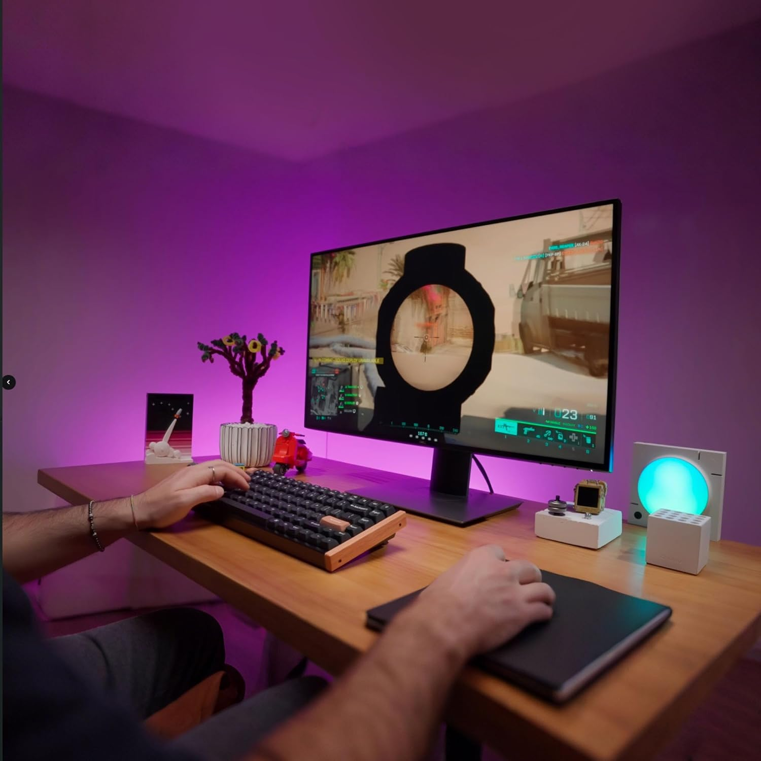 Osoba gra na klawiaturze i myszy na drewnianym biurku. Monitor wyświetla grę.