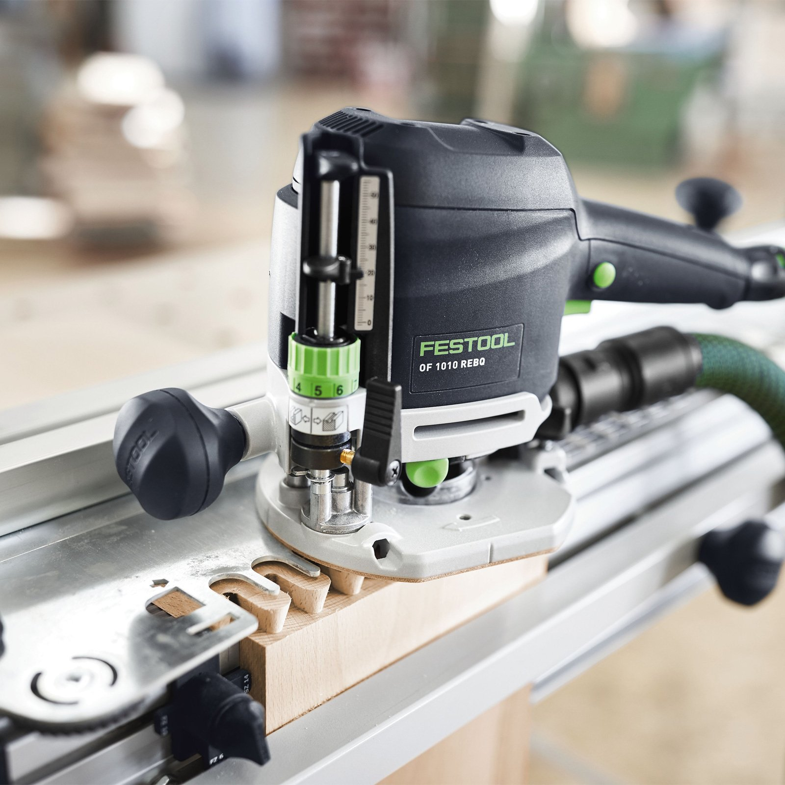 Schwarz-grünes Elektrowerkzeug, bohrt mit Führung in Holz.