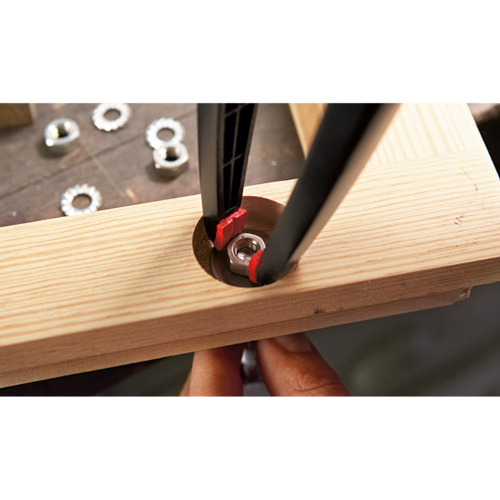 Primer plano de un perno apretándose con una herramienta en una superficie de madera. Otro hardware es visible.