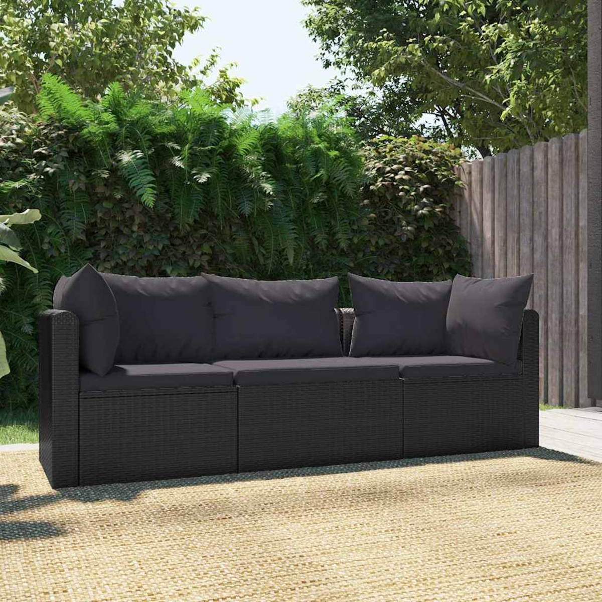 Schwarzes Rattan-Sofa mit grauen Kissen. Dreisitziges Sofa auf einem Teppich.