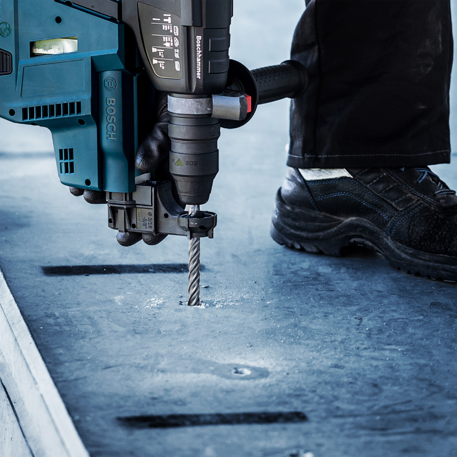Osoba wierci w betonie młotowiertarką Bosch. Zbliżenie pokazuje wiertło wchodzące w materiał.