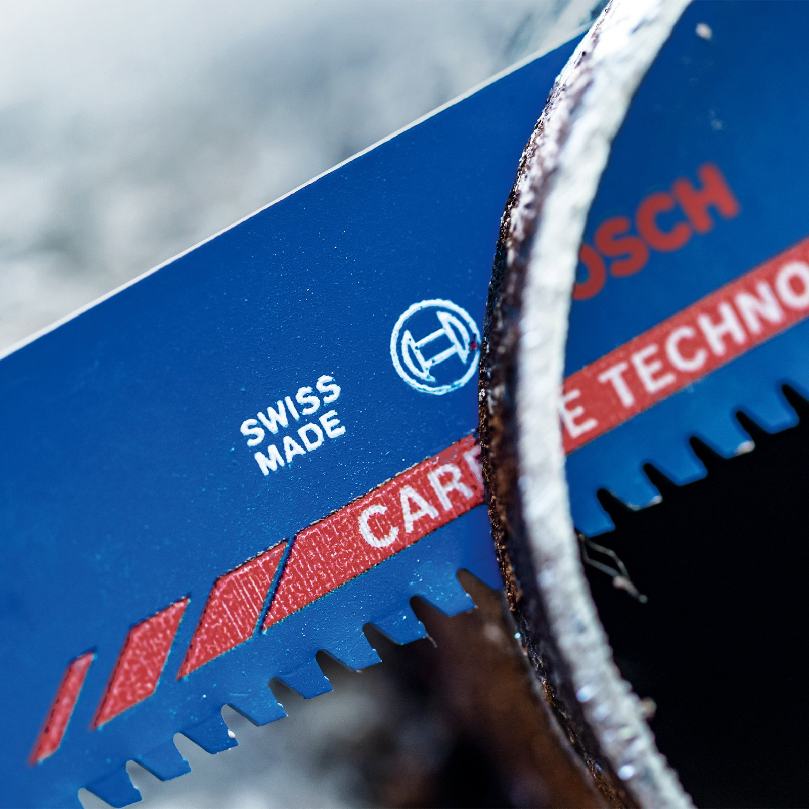 Zbliżenie niebieskiego brzeszczotu z czerwonymi akcentami, logo Bosch i metalową rurą.