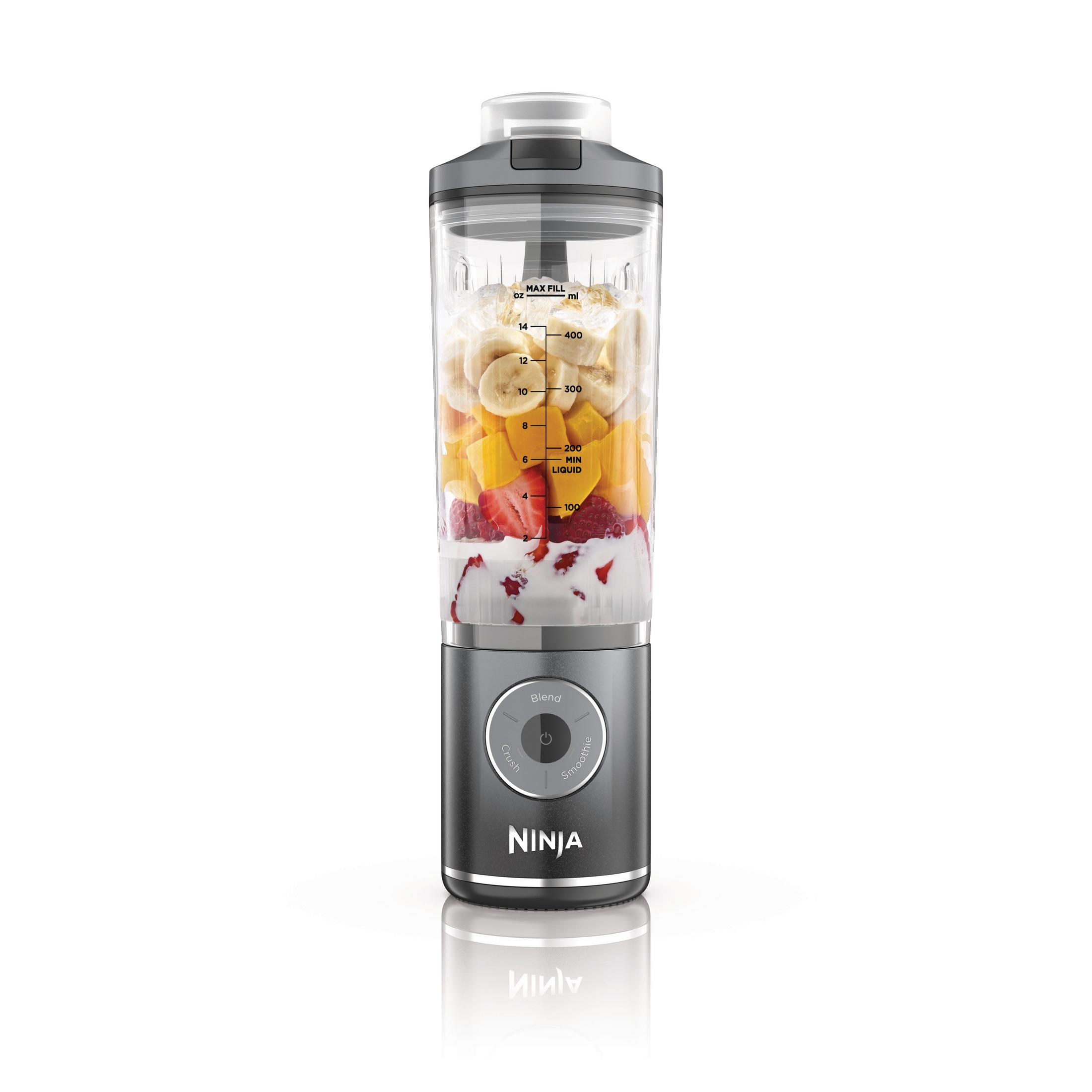 Ein Mixer mit Früchten im Inneren. Bananen, Mangos, Erdbeeren und Joghurt sind sichtbar. Der Mixer steht auf einer weißen Oberfläche.
