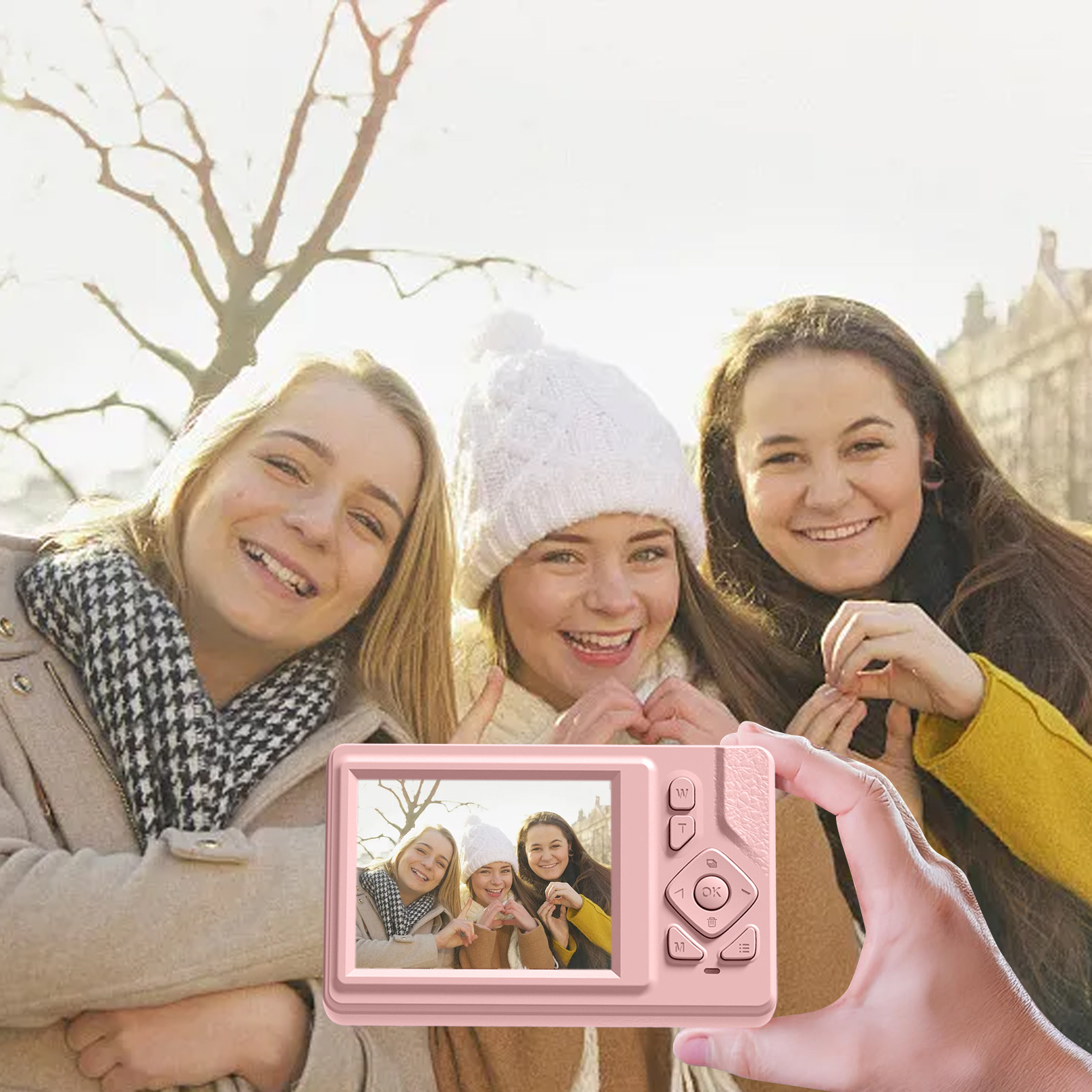 Drei junge Frauen lächeln und halten eine rosa Kamera. Die Kamera zeigt ein Foto von ihnen. Stadt im Hintergrund.
