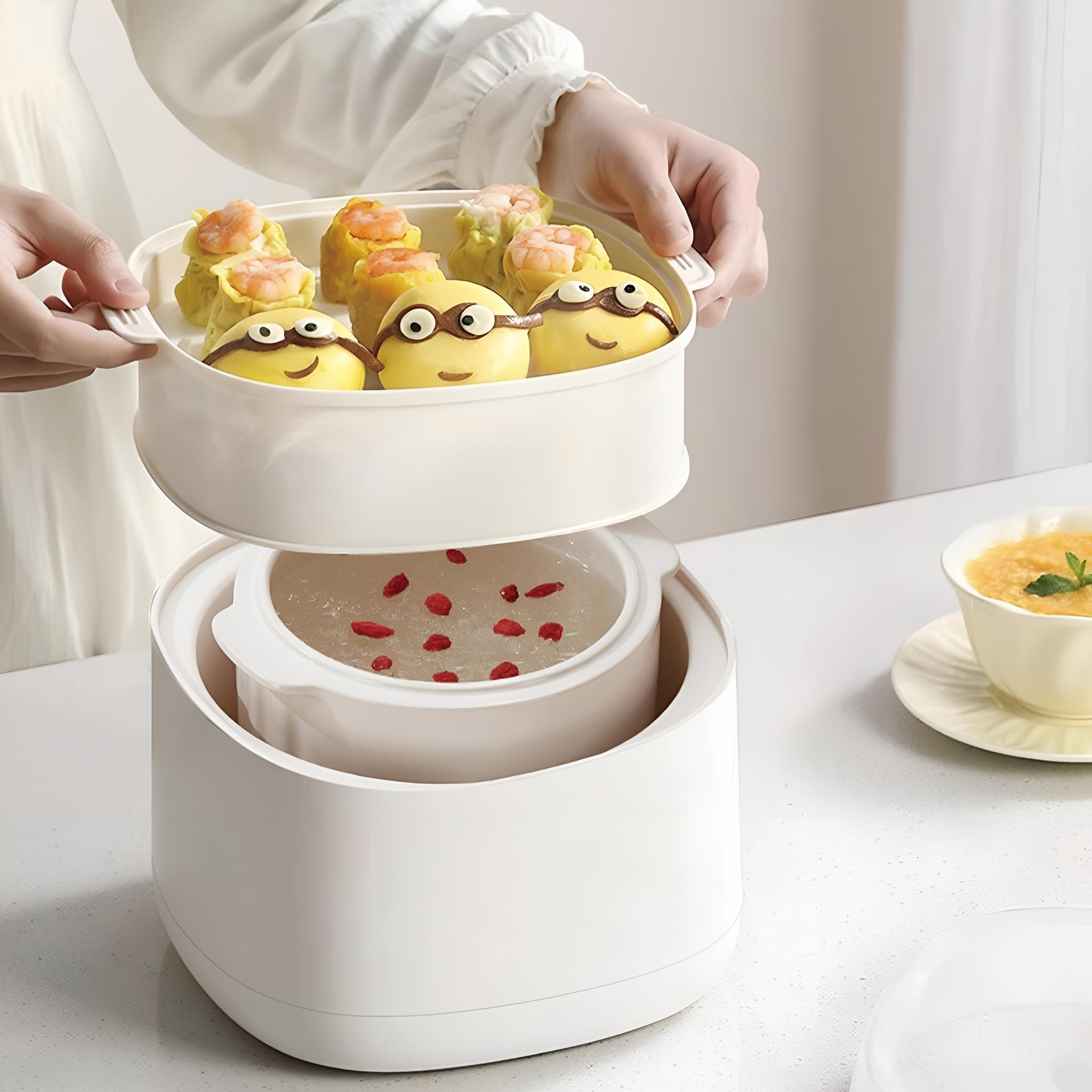 Eine Person hält einen weißen Dampfgarer mit Essen darin. Gelbe Brötchen mit Augen und Garnelenknödel sind sichtbar.
