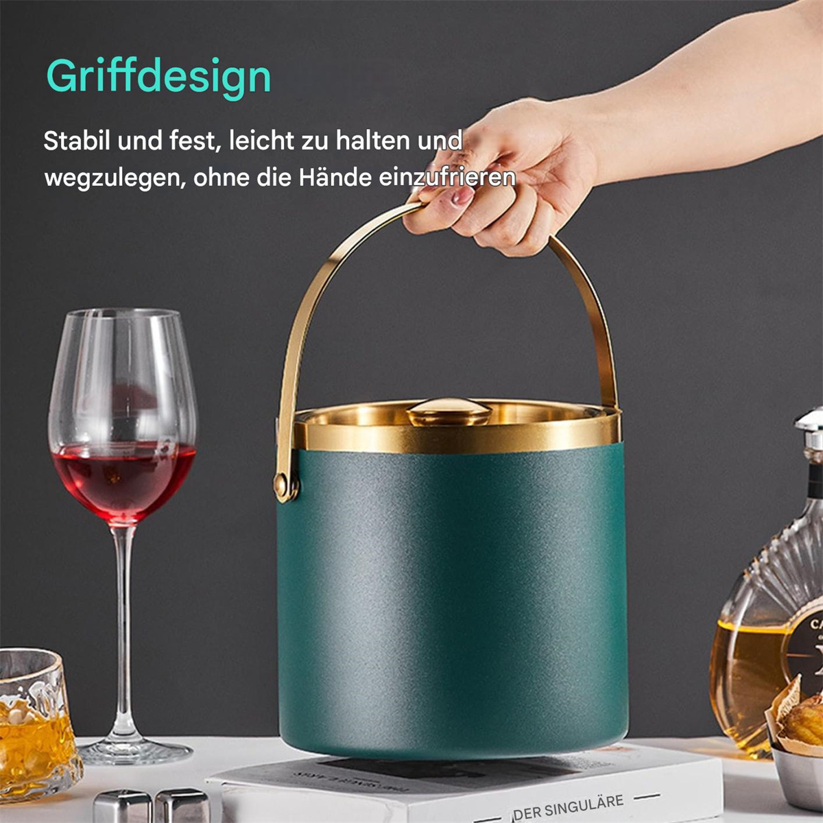 Hand hält einen tealfarbenen Eiskübel mit goldenem Rand. Im Hintergrund sind ein Weinglas und Likörflaschen.