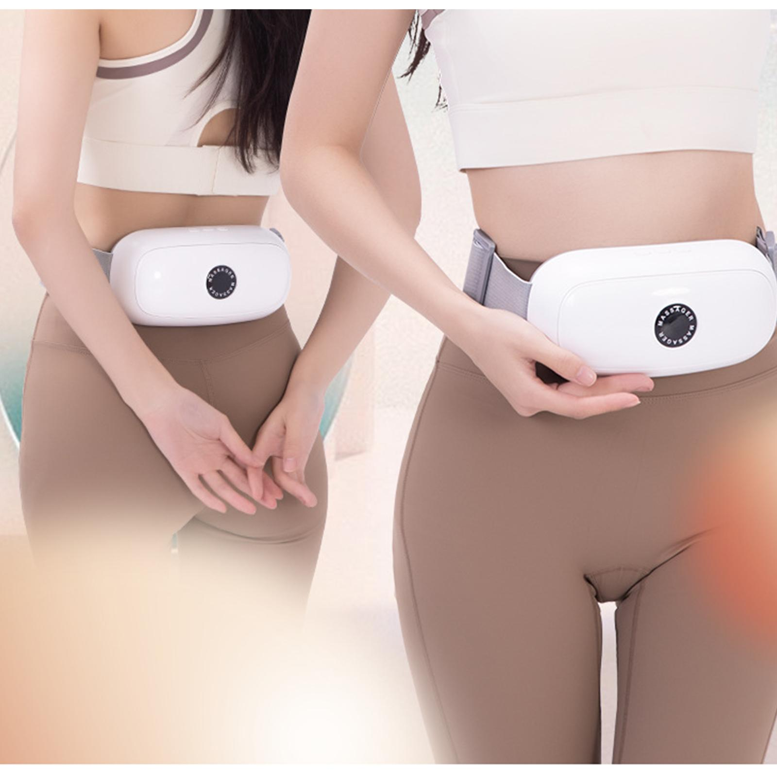 Zwei Frauen tragen weiße Gürtelmassagegeräte um die Taille. Beide tragen Sportkleidung, eine hat die Hand auf dem Rücken.