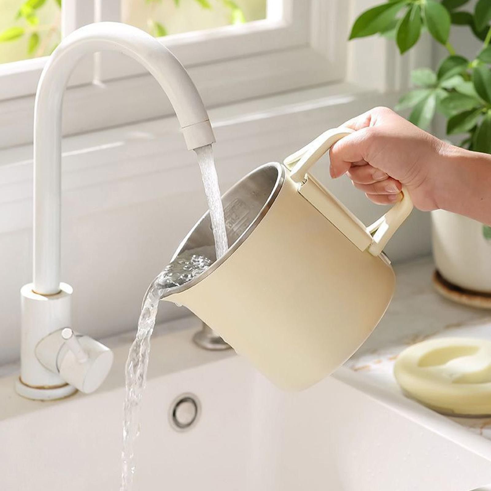 Eine Hand gießt Wasser aus einem cremefarbenen Krug in ein Waschbecken. Weißer Wasserhahn und Fenster im Hintergrund.