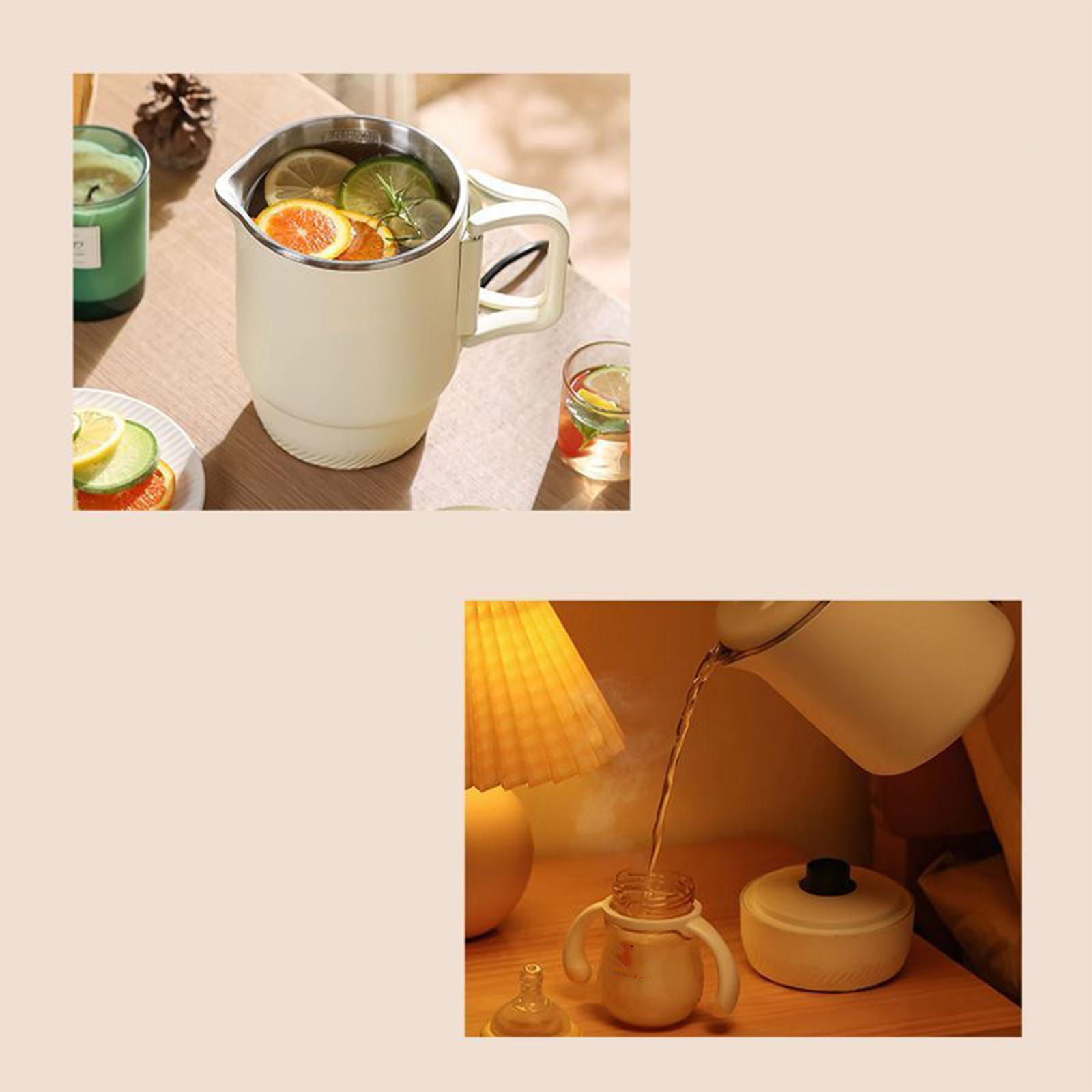 Ein cremefarbener Wasserkocher mit Zitrusfrüchten, ein Glas mit Früchten und eine Lampe stehen auf einem Holztisch.