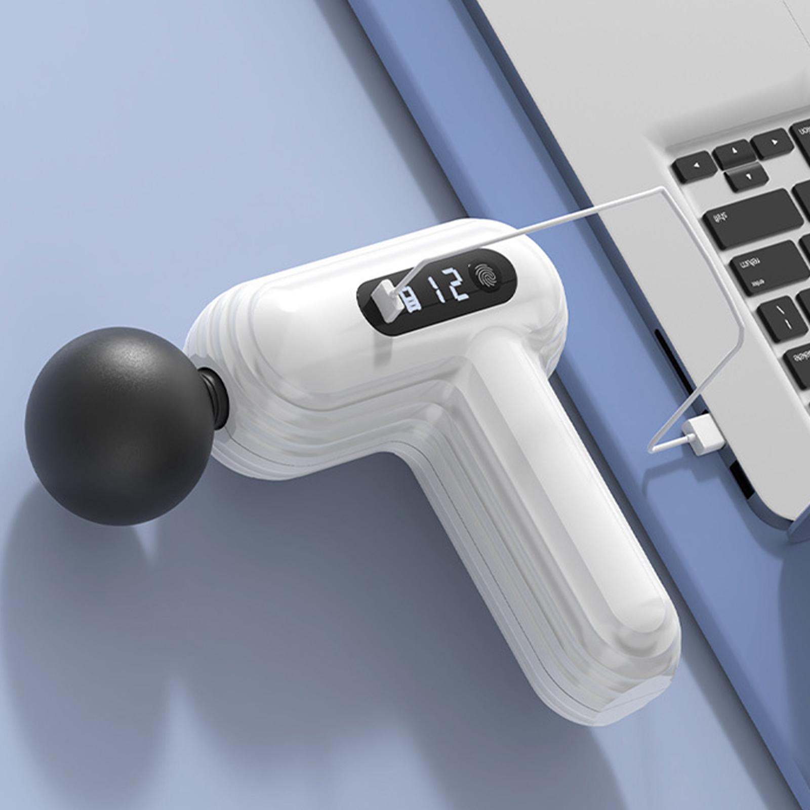 Weiße Massagepistole, die von einem Laptop aufgeladen wird. Pistole auf blauem Untergrund. Die Pistole hat einen schwarzen Kopf.