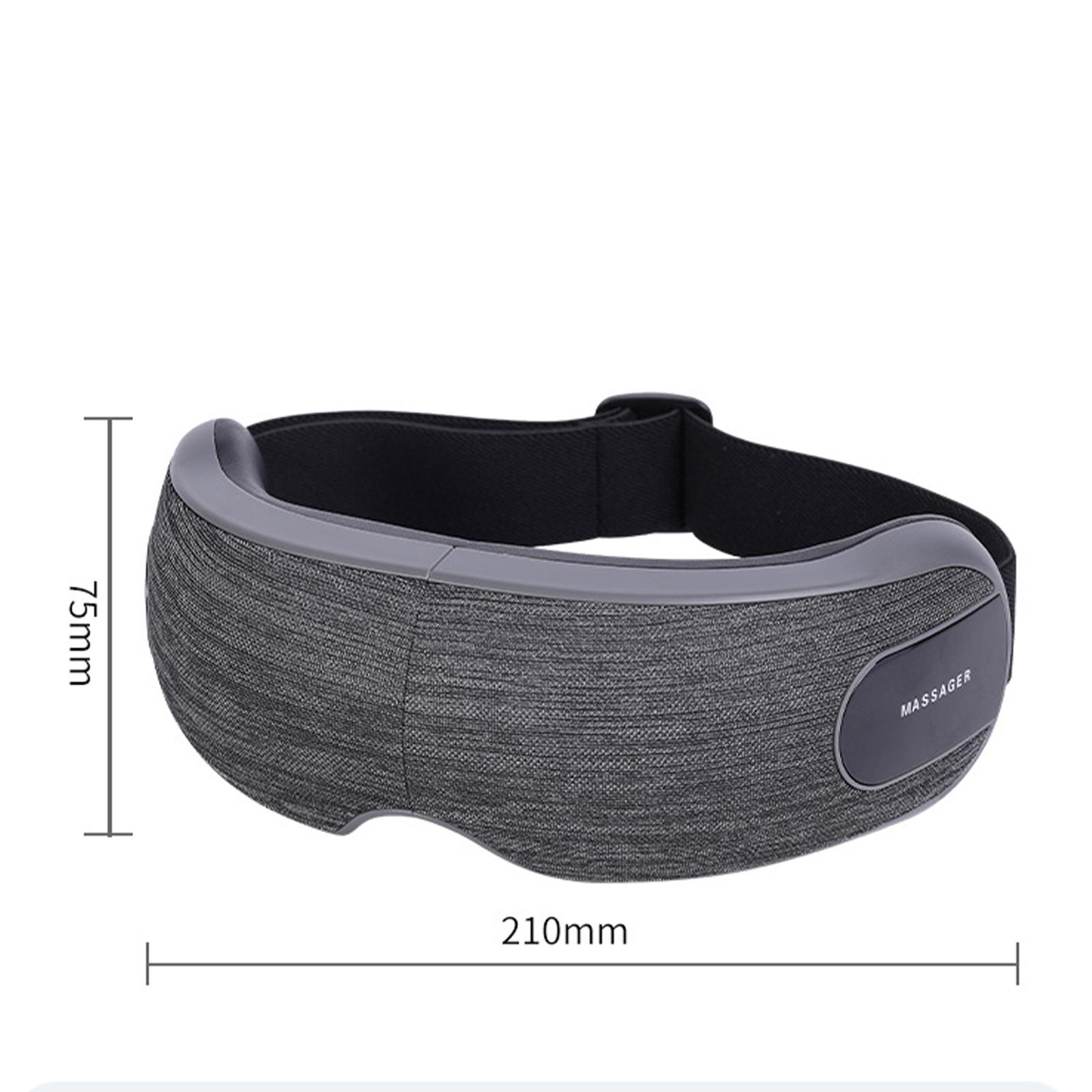 Graues Augenmassagegerät mit schwarzem Riemen. Es ist 210 mm lang und 75 mm hoch. Es hat ein 'MASSAGER'-Etikett.