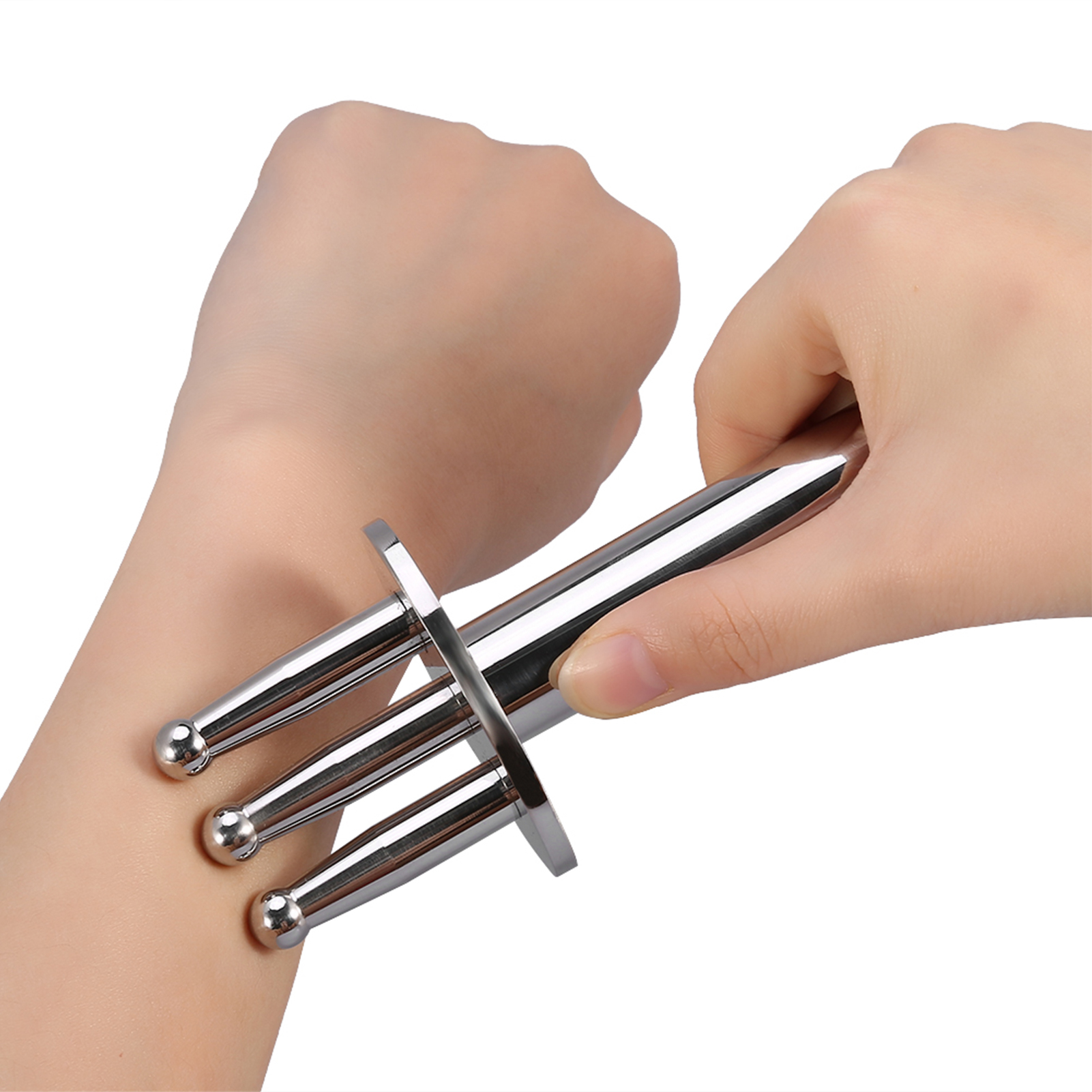 Hände halten ein silbernes Massagegerät. Das Werkzeug hat drei abgerundete Zinken. Eine Hand hält es, die andere ruht auf einem Arm.